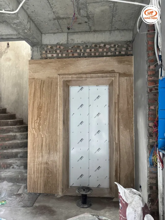 Mặt tiền thang máy ốp đá vân gỗ tự nhiên