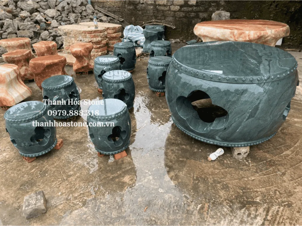 Hình ảnh cận cảnh một bộ bàn ghế đá tự nhiên với các ghế tròn nhỏ và bàn tiện trống, tạo cảm giác hài hòa cho sân vườn