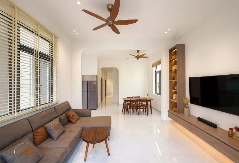 Trang trí phòng khách đơn giản cho nhà cấp 4 với trần thạch cao phẳng, hệ đèn LED âm trần gọn gàng, sofa vải tối màu tạo cảm giác ấm cúng