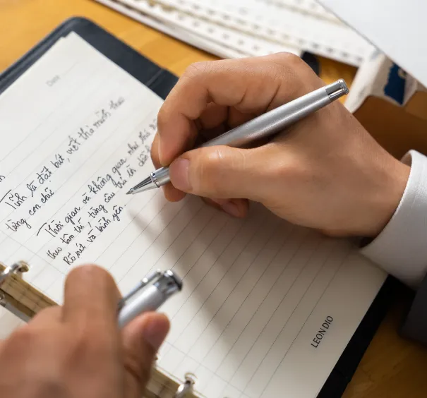 Bàn làm việc được sắp xếp gọn gàng với sổ da cao cấp, khay đựng hồ sơ và vật dụng trang trí